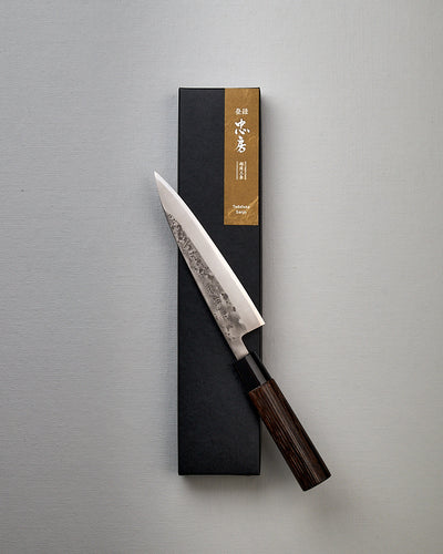 A Tadafusa Bocho Petty Knife in a box on a white surface.