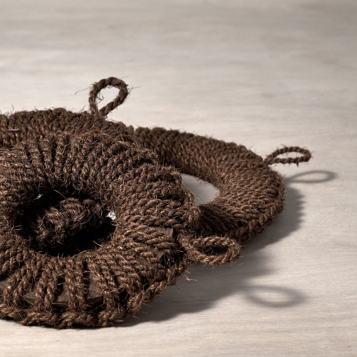 Three Hand-Knit Trivet – Small by Takada on a wooden surface.