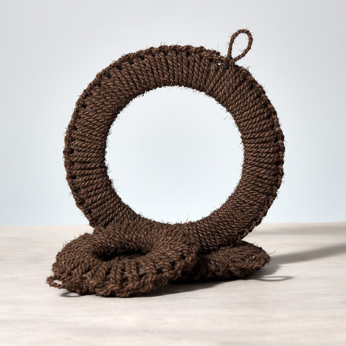 A Hand-Knit Trivet – Small by Takada on top of a wooden table.