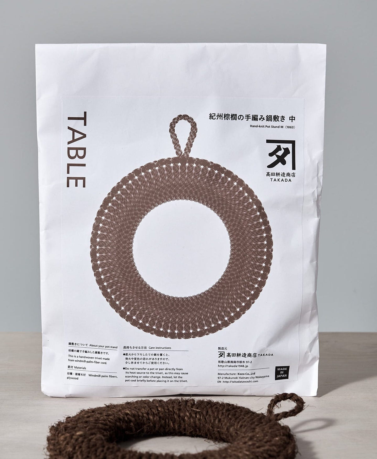 A bag of Hand-Knit Trivet – Medium with a Takada table on it.