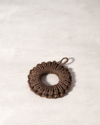 A Takada Hand-Knit Trivet – Small brown rope ornament on a white surface.