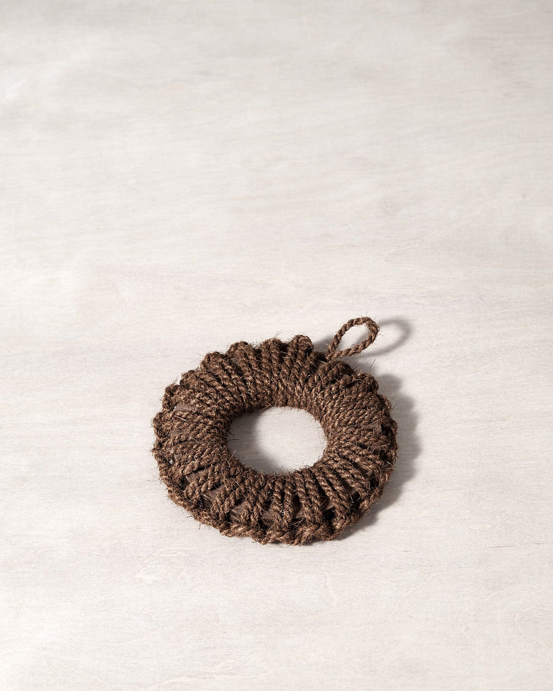 A Takada Hand-Knit Trivet – Small brown rope ornament on a white surface.