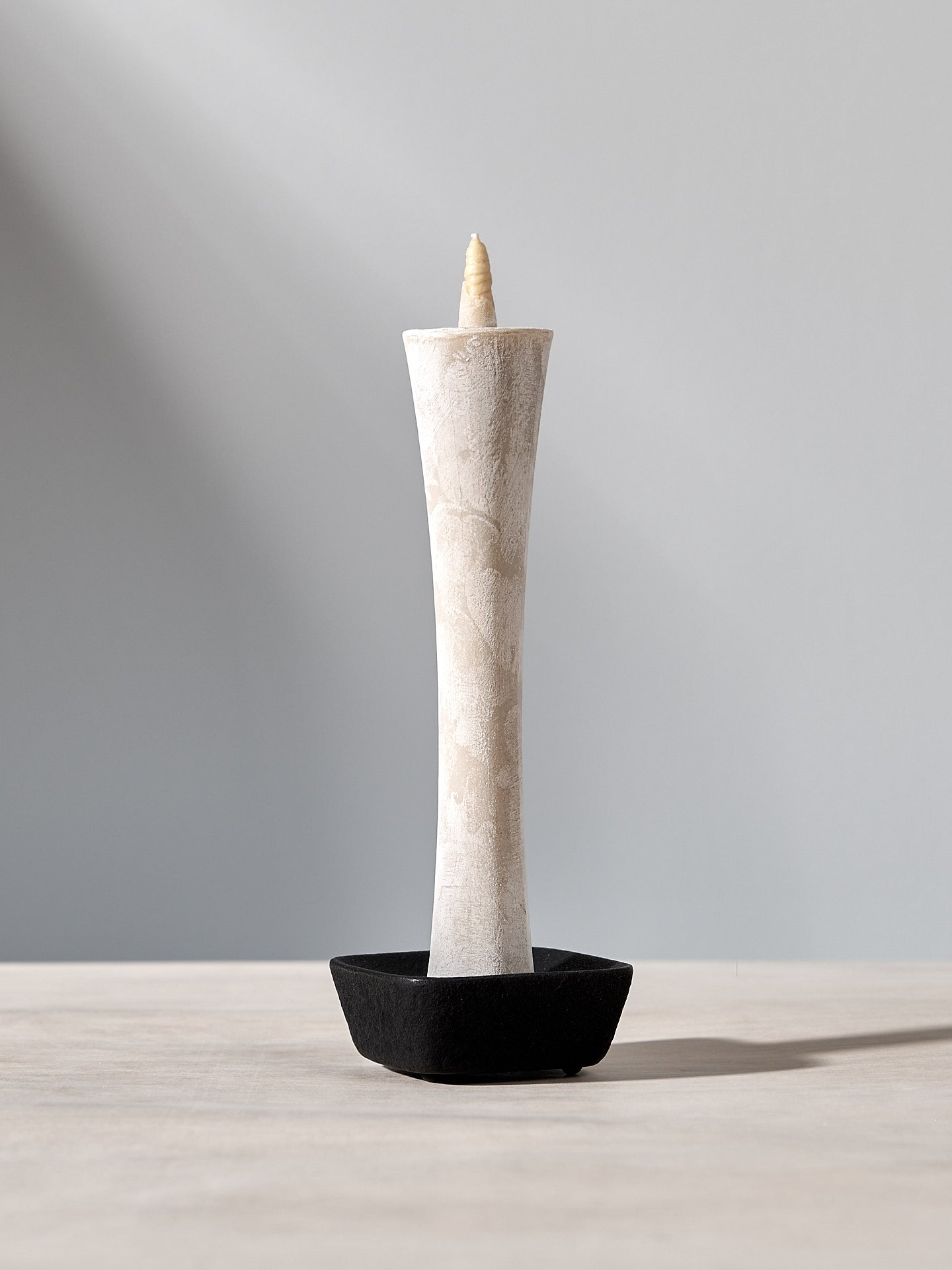 A Takazawa IKARI Candle – Large (box of 1) is sitting on a table with a black base.