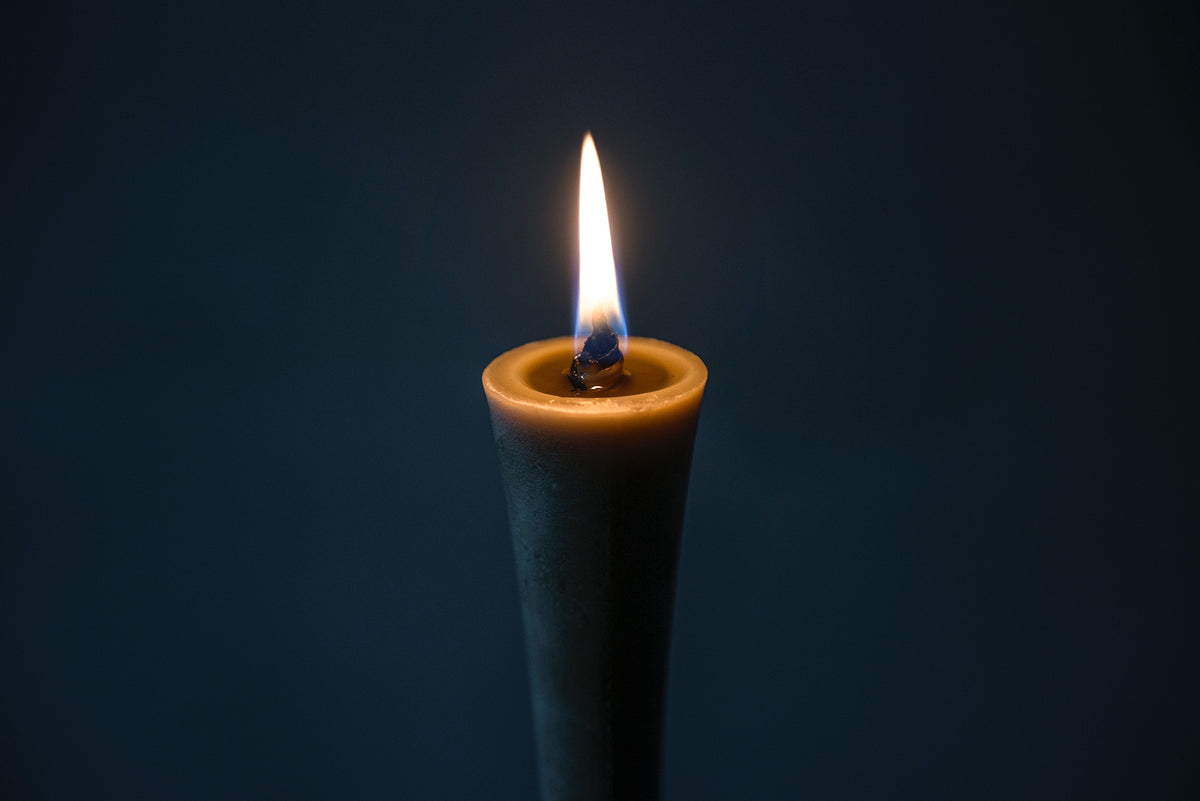 An IKARI Candle – Large (box of 1) by Takazawa is lit on a dark background.
