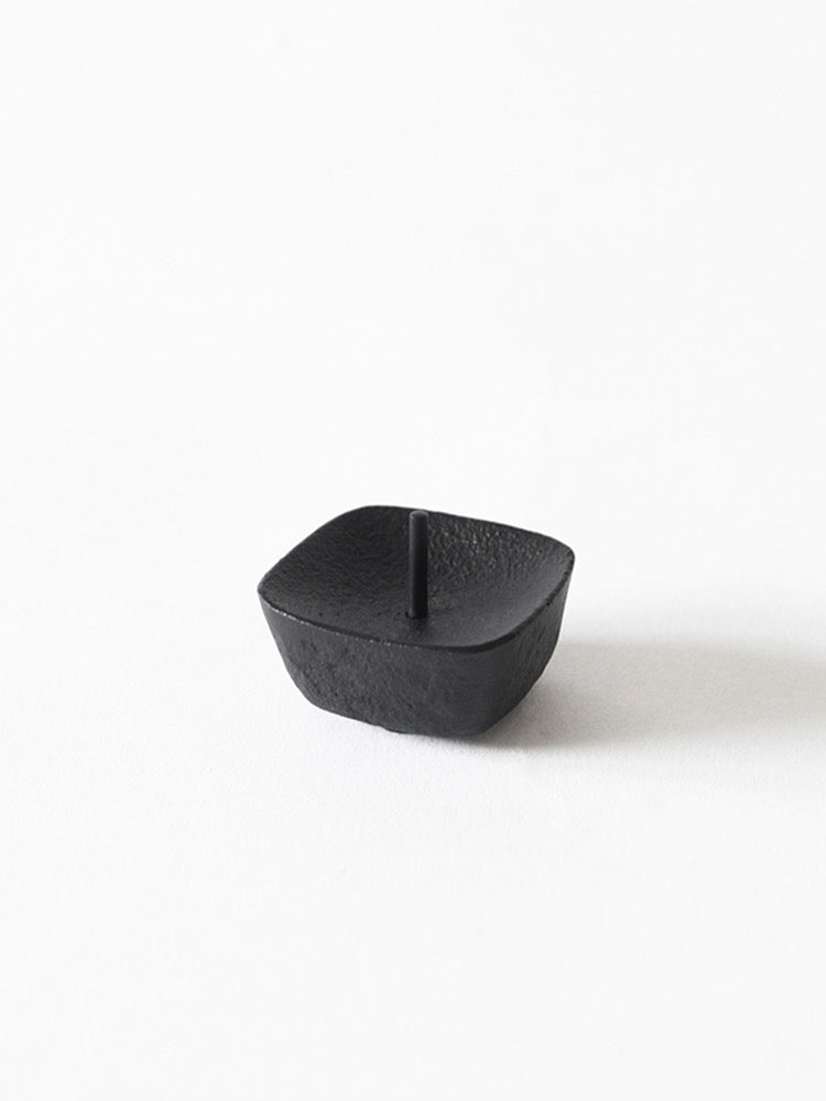 A small black KOMA Iron Candle Stand – Small by Takazawa on a white surface.