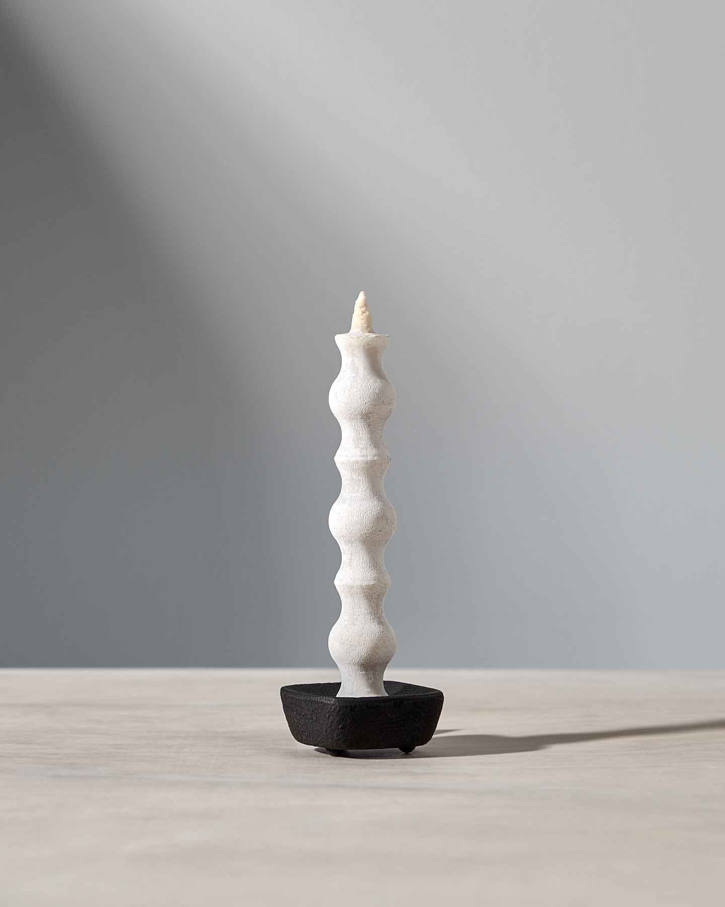 A NANAO-L candle is sitting on a table with a light behind it. [Brand name: Takazawa]
