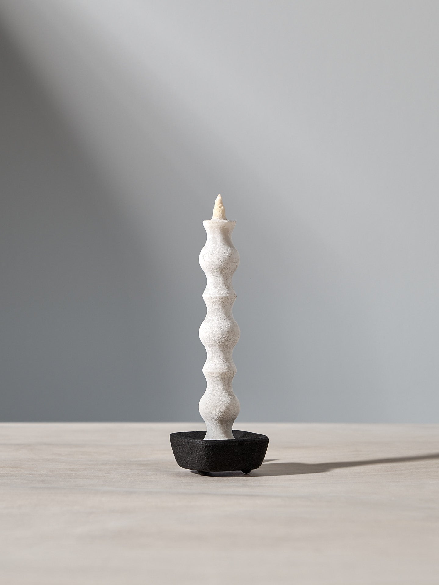 A NANAO-L candle is sitting on a table with a light behind it. [Brand name: Takazawa]