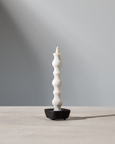 A NANAO-L candle is sitting on a table with a light behind it. [Brand name: Takazawa]