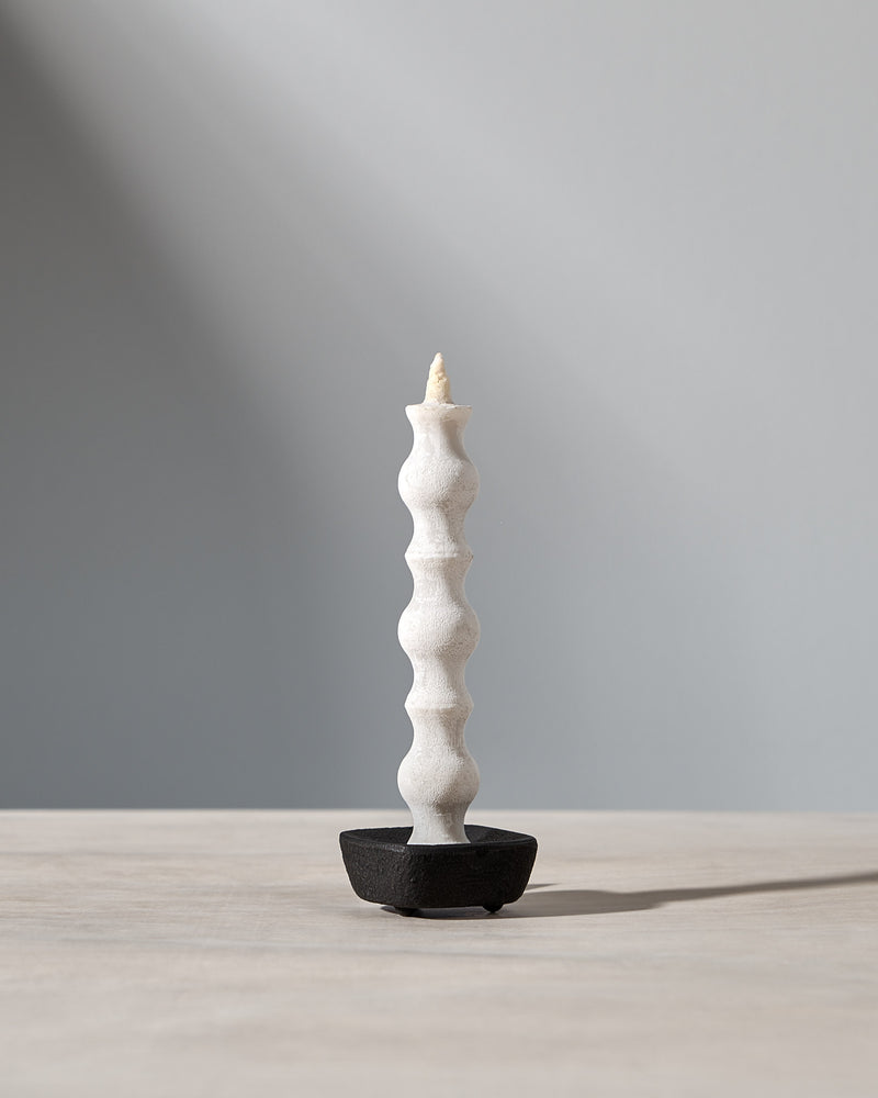 A NANAO-L candle is sitting on a table with a light behind it. [Brand name: Takazawa]