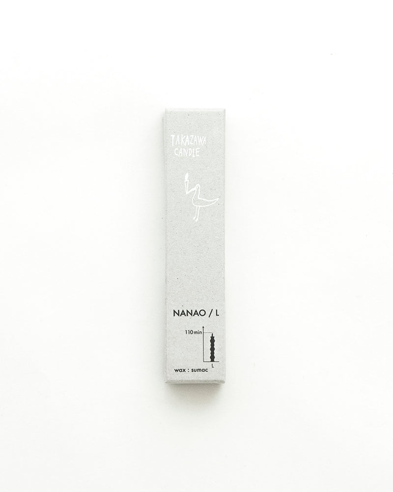A NANAO-L candle is sitting on a table with a light behind it. [Brand name: Takazawa]