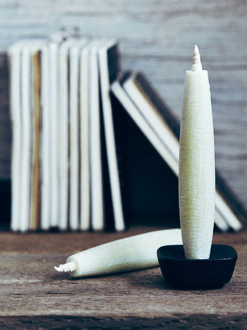 A TOHAKU Candle - Large (box of 1) sits on a wooden table next to books.