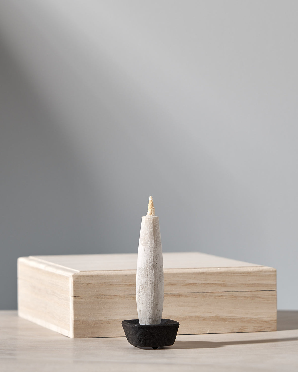An Elegant gift set, consisting of a candle sitting on top of a wooden box, with a Takazawa cast iron candle holder complementing the TOHAKU – Small (8 piece box set) candles.