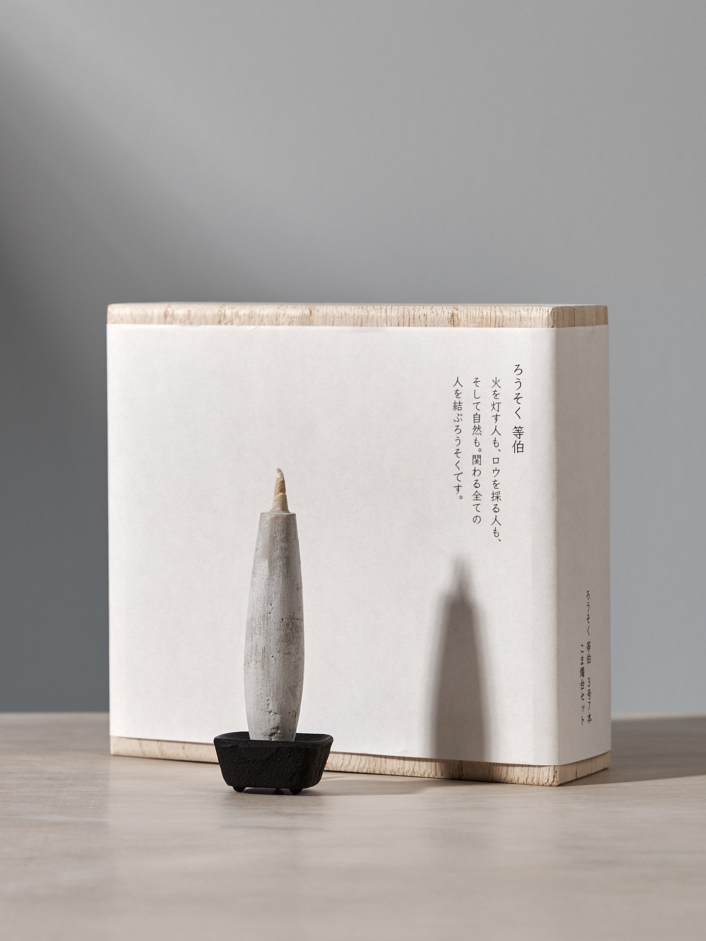 A box with an elegant gift set consisting of a Koma cast iron candle holder and Takazawa TOHAKU – Small (8 piece box set) candles sitting on top of it.