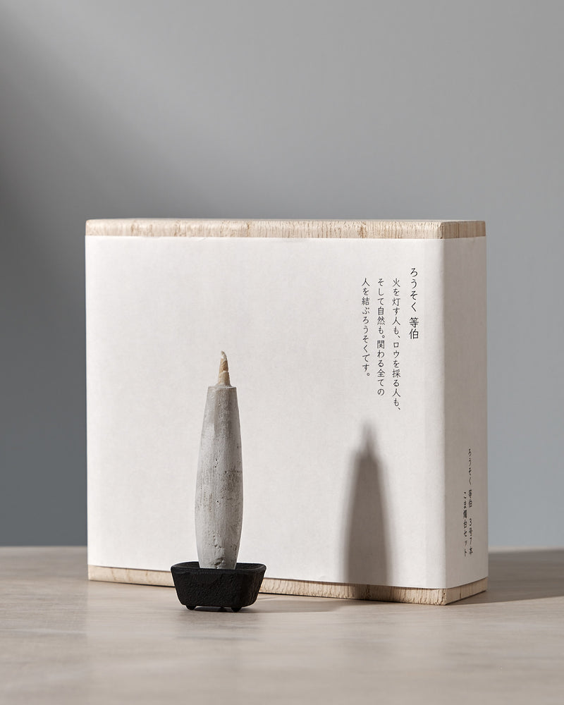 A box with an elegant gift set consisting of a Koma cast iron candle holder and Takazawa TOHAKU – Small (8 piece box set) candles sitting on top of it.