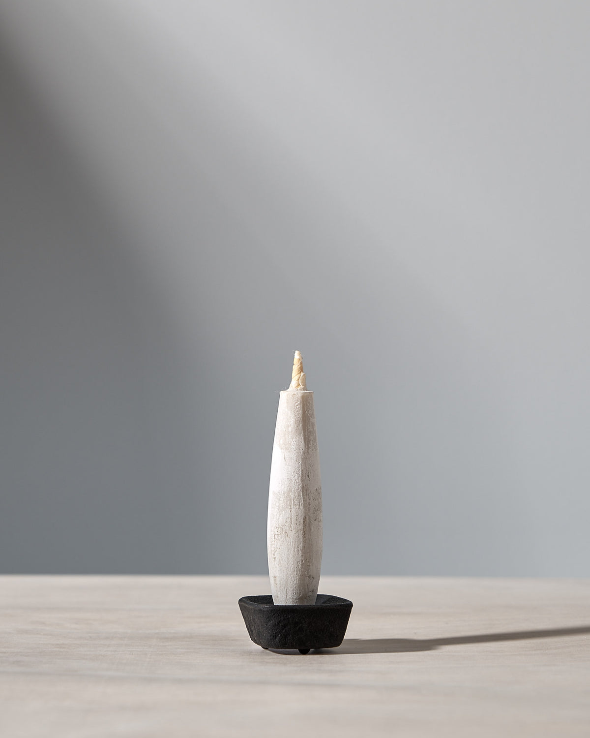 An elegant gift set featuring a Takazawa TOHAKU – Small (8 piece box set) candle beautifully displayed on a wooden table with a Koma cast iron candle holder.