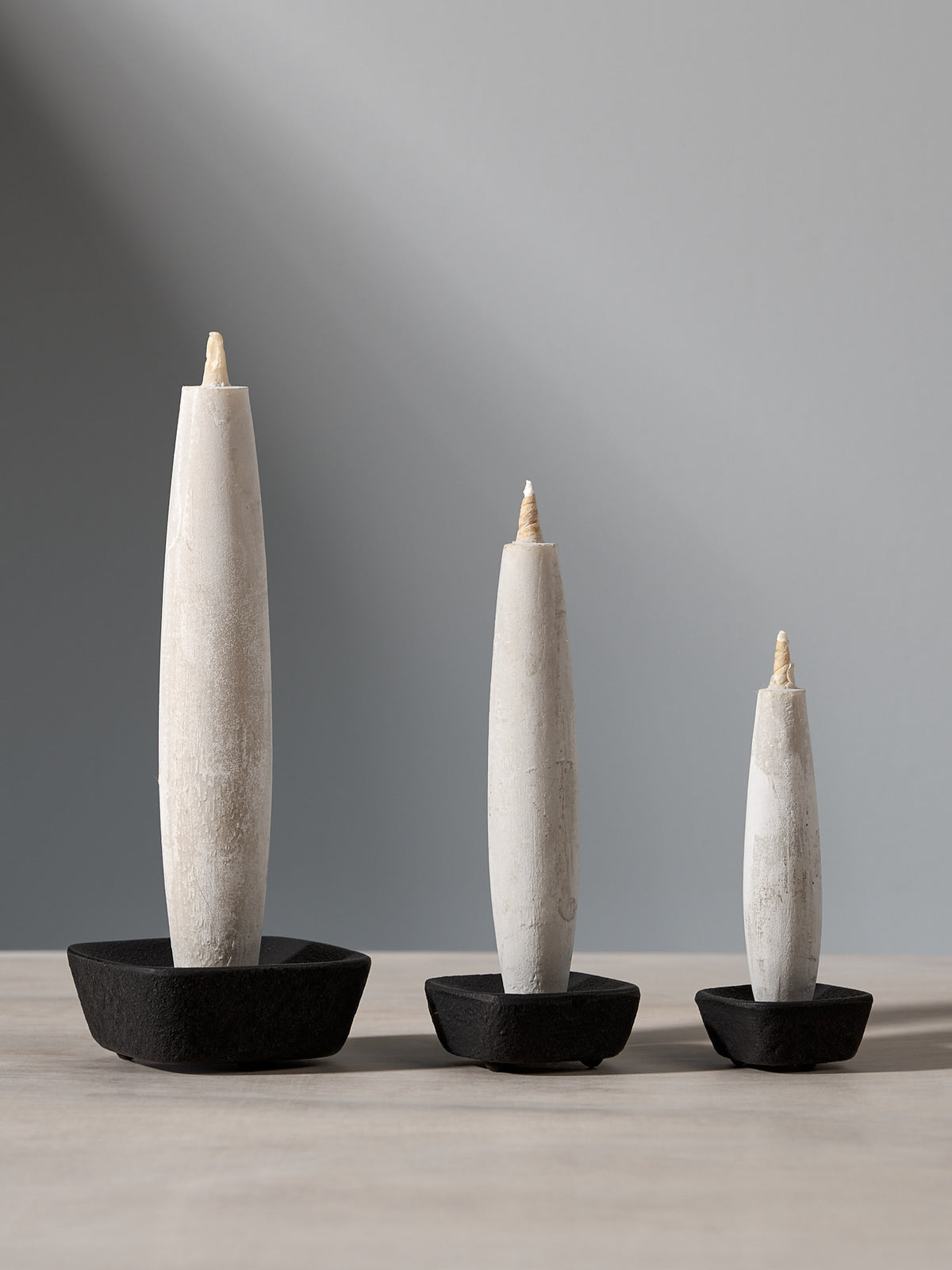 Three TOHAKU Candle – Large (box of 1) holders sitting on a table.