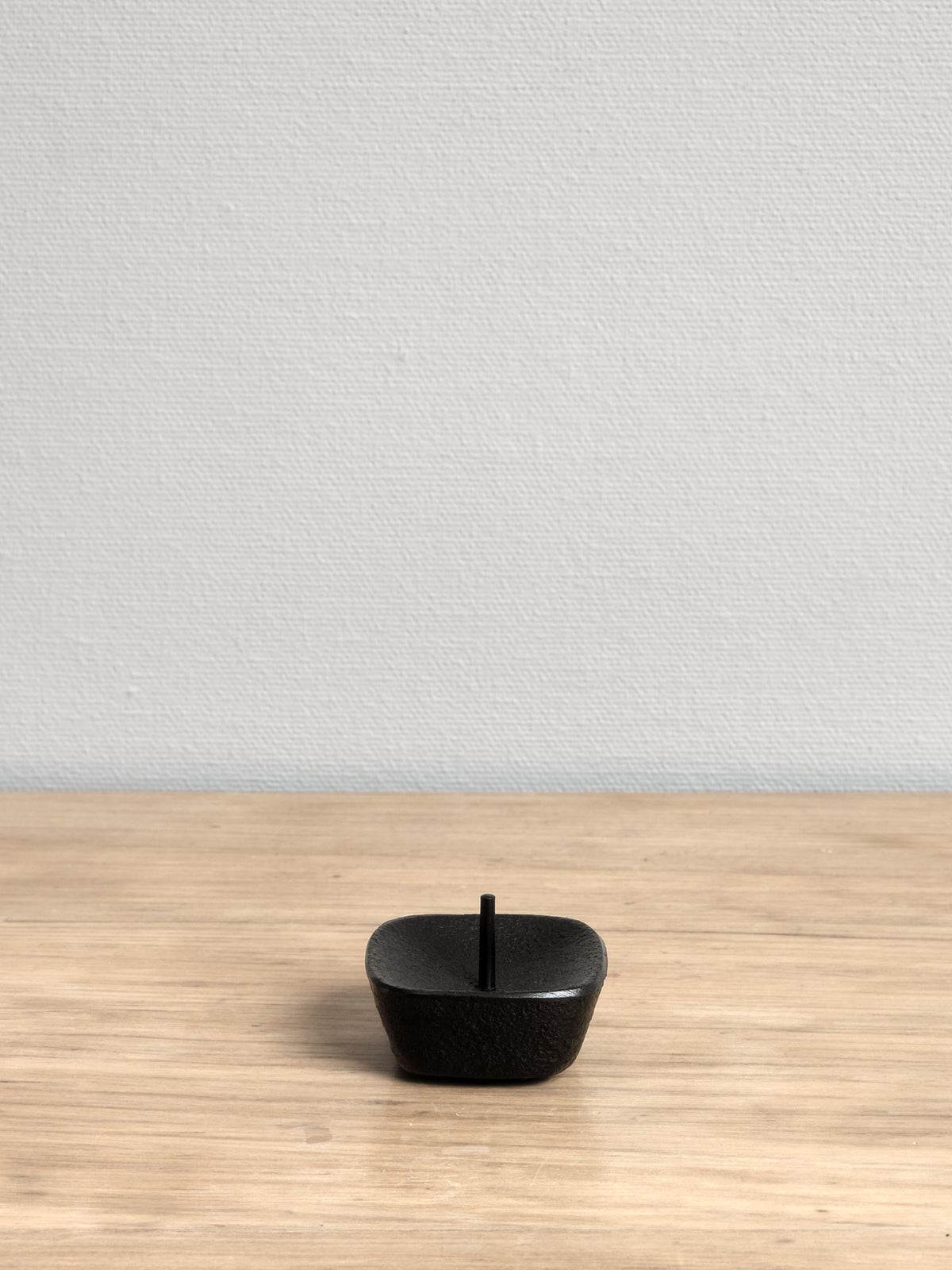 A Takazawa KOMA Iron Candle Stand - Small sitting on a wooden table.