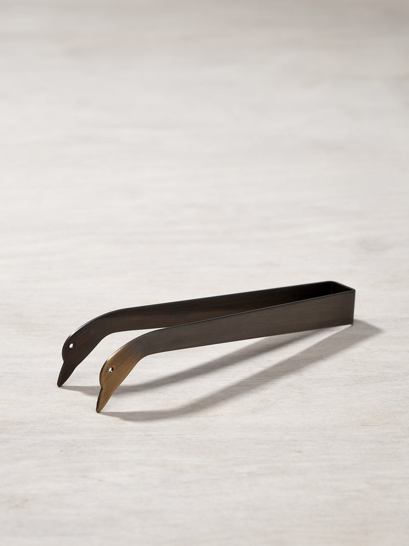 A pair of Candle Snuffer Ducks by Takazawa on a wooden surface.