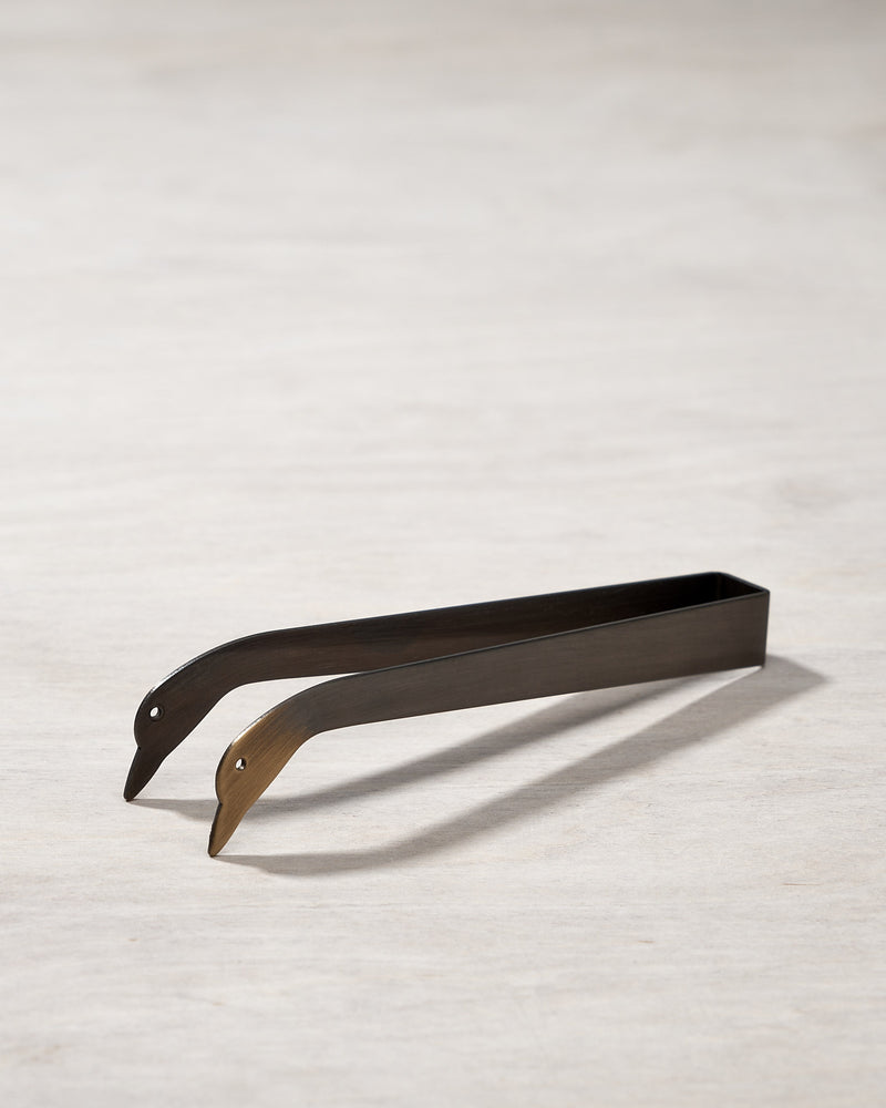 A pair of Candle Snuffer Ducks by Takazawa on a wooden surface.