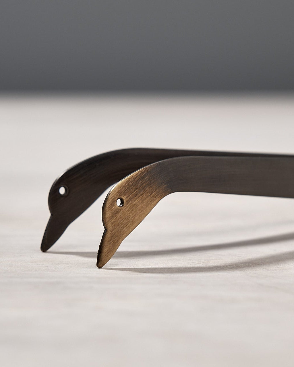 A pair of Candle Snuffer Ducks by Takazawa on a wooden surface.