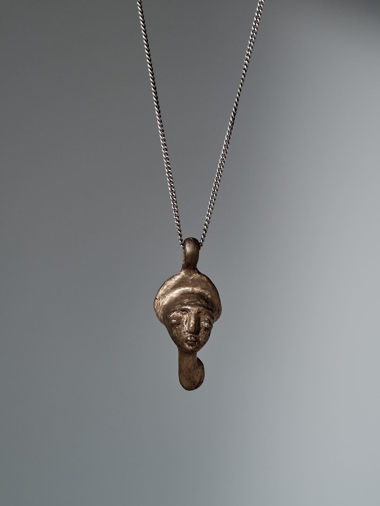 A Talisman Pendant necklace with a bronze head on it by Tamara Rookes.