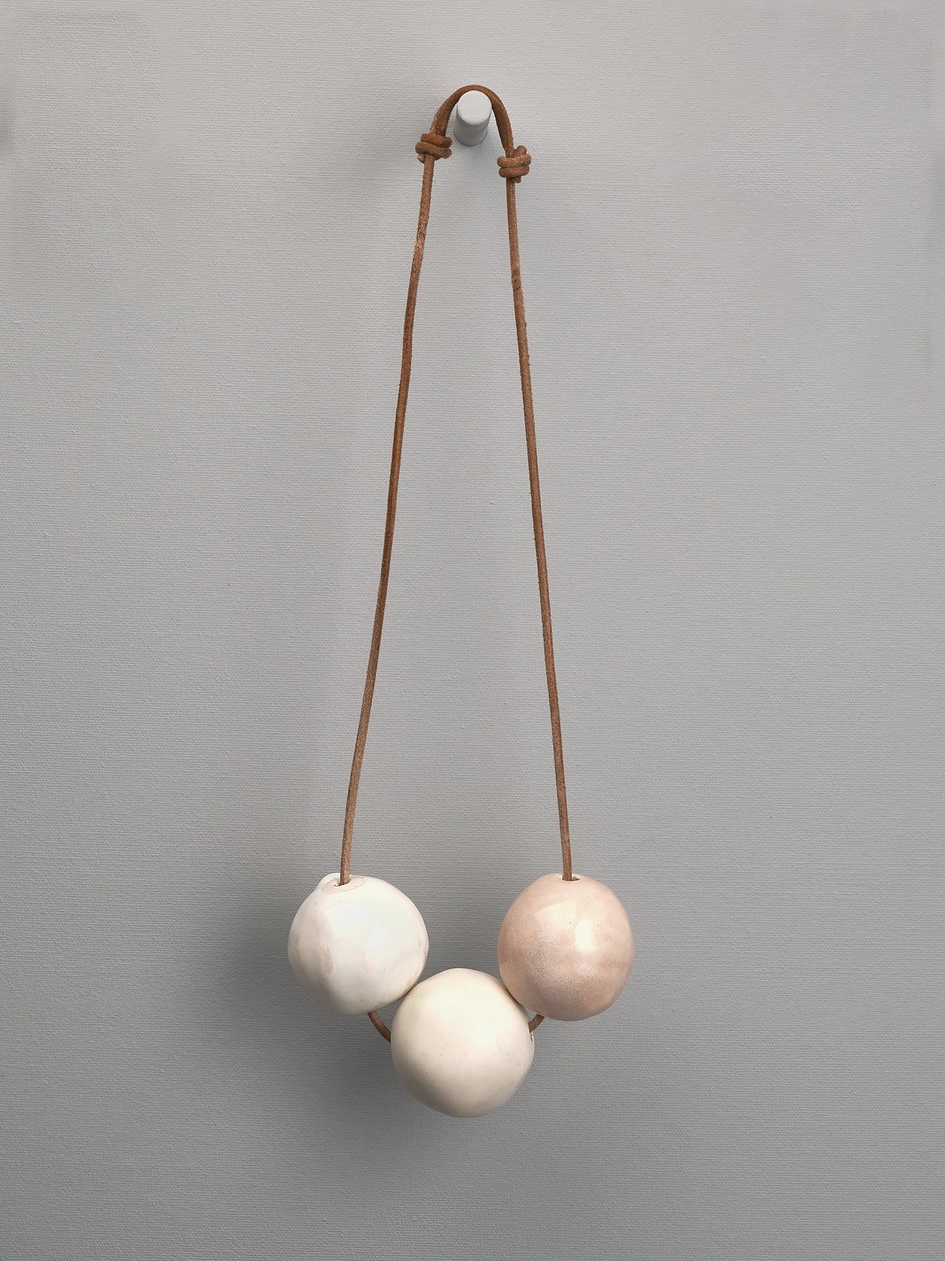 A necklace with three Ceramic Beads – Ø 50𝗆𝗆, from the brand Tamara Rookes, hanging from a rope.
