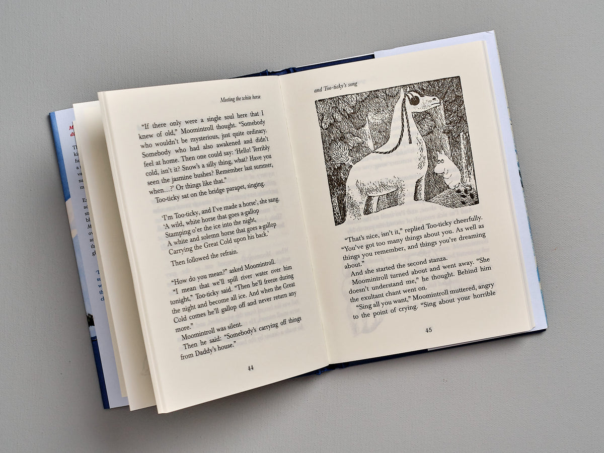 An open book with a picture of Moominland Midwinter by Tove Jansson.