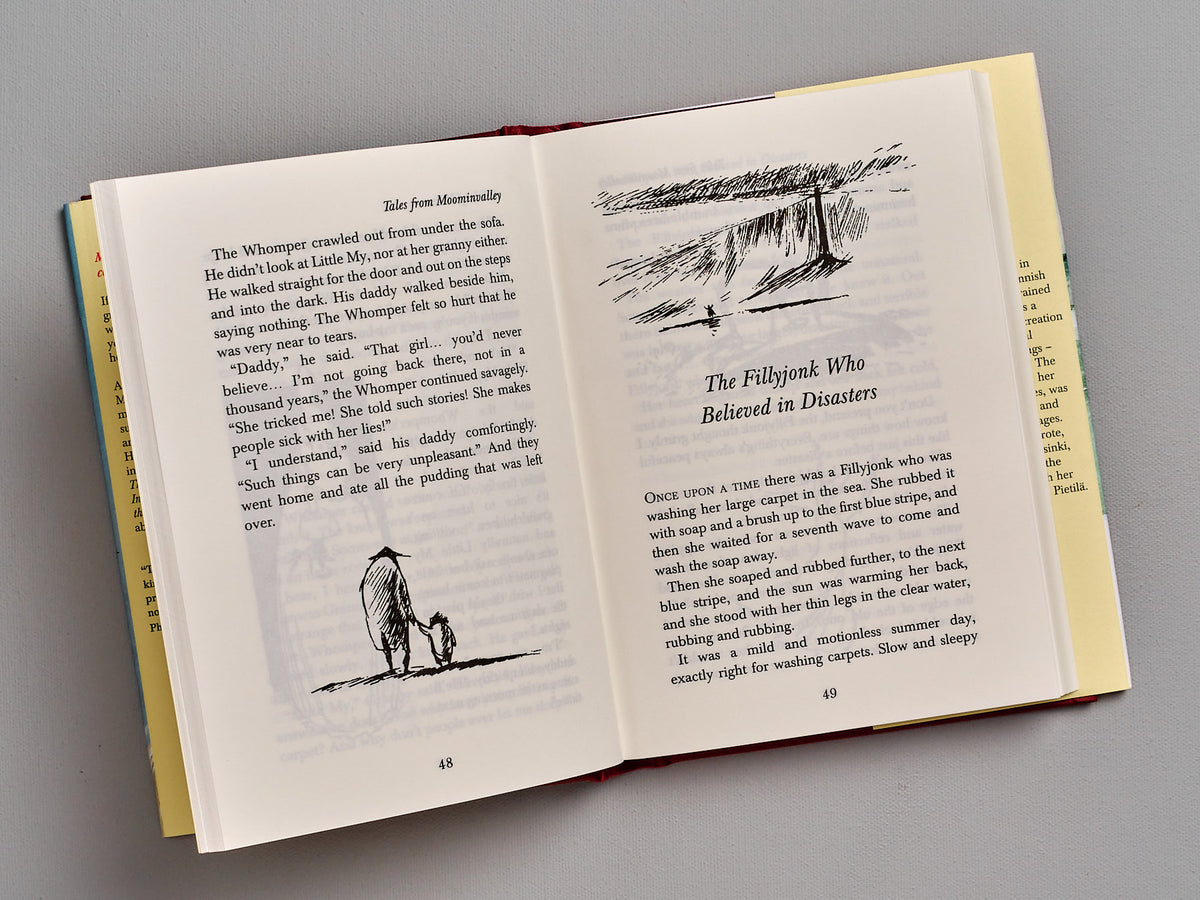An open book of &quot;Tales From Moominvalley&quot; by Tove Jansson with a picture of a man and a dog.