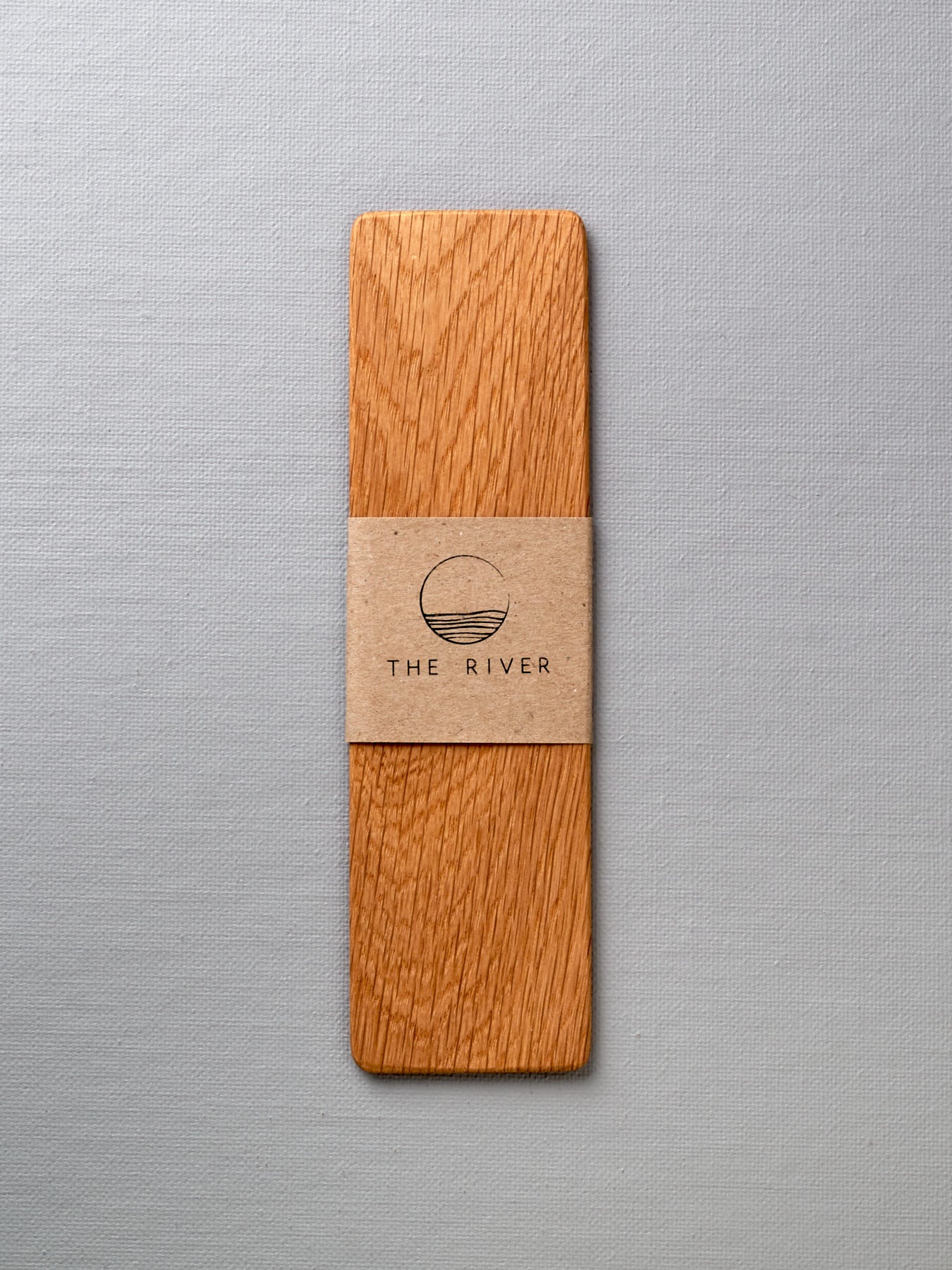 A Bookmark - Oak cutting board with a label on it made by The River.