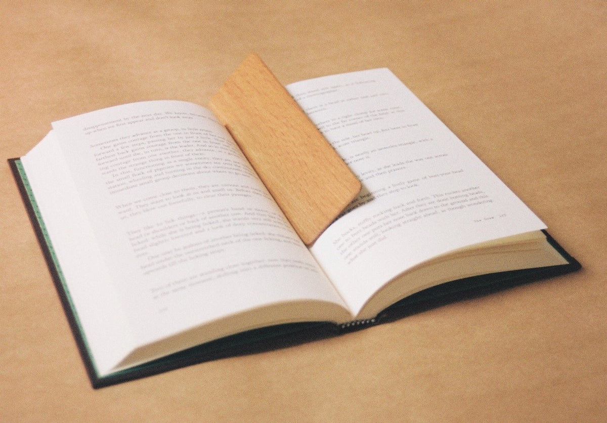 An open book with The River - Oak Bookmark.