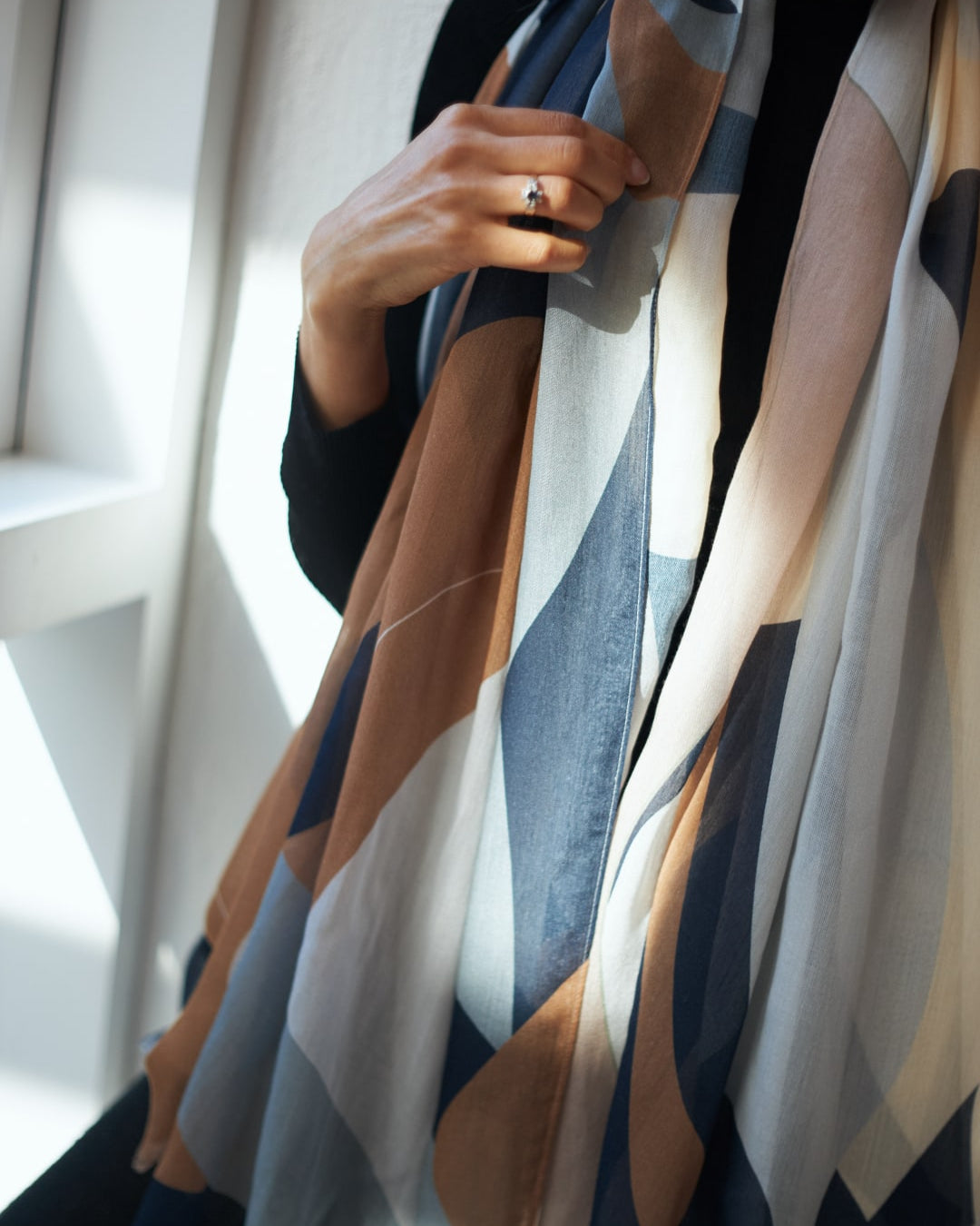 A woman wearing a Rosemary Scarf by Walker & Bing with a geometric pattern.