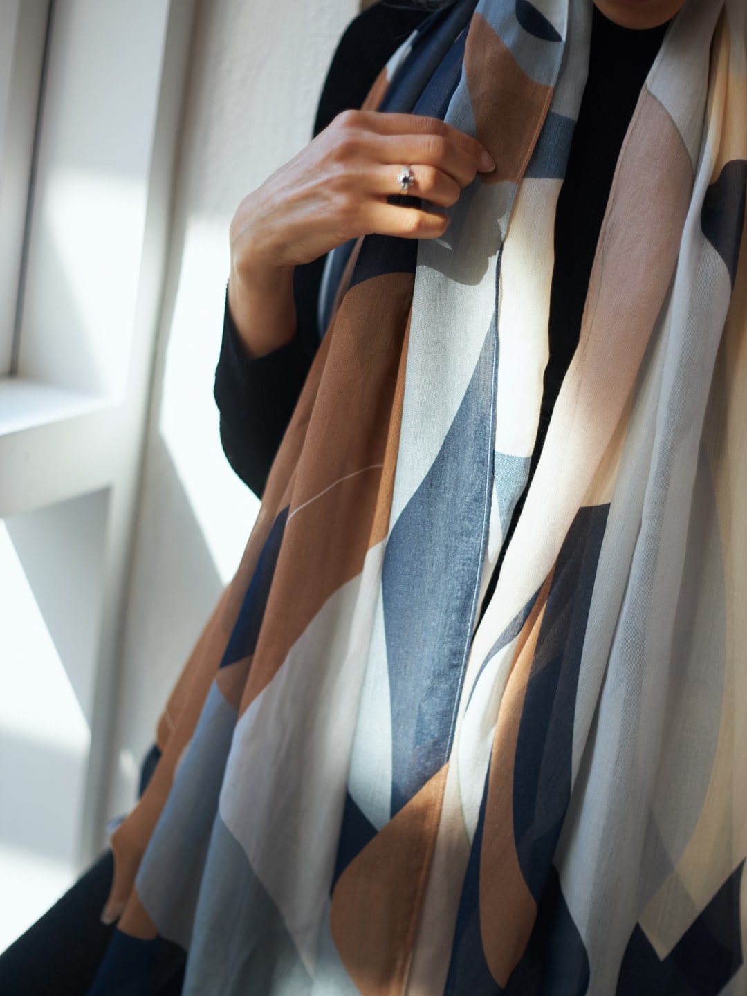 A woman wearing a Rosemary Scarf by Walker &amp; Bing with a geometric pattern.