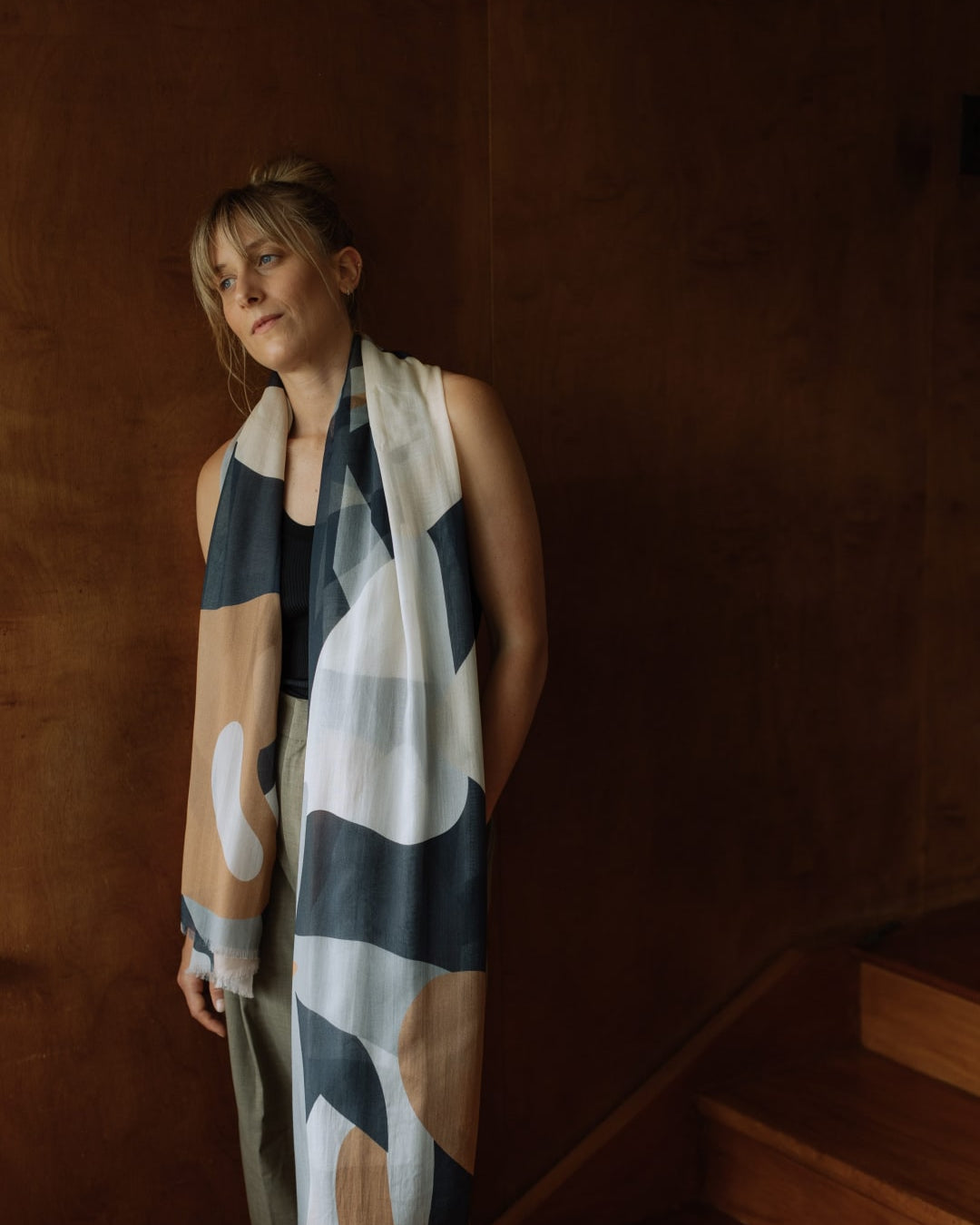 A woman wearing a Walker & Bing Rosemary Scarf standing on a staircase.