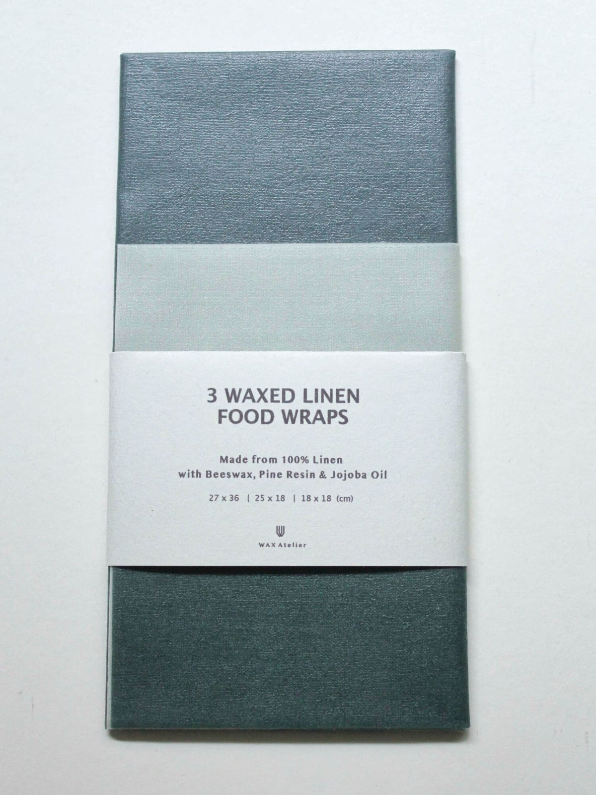 Three stacked Waxed Linen Food Wraps (Set of 3) – Ivy ⋄ Madder ⋄ Indigo packaging, a sustainable alternative on a white background by Wax Atelier.