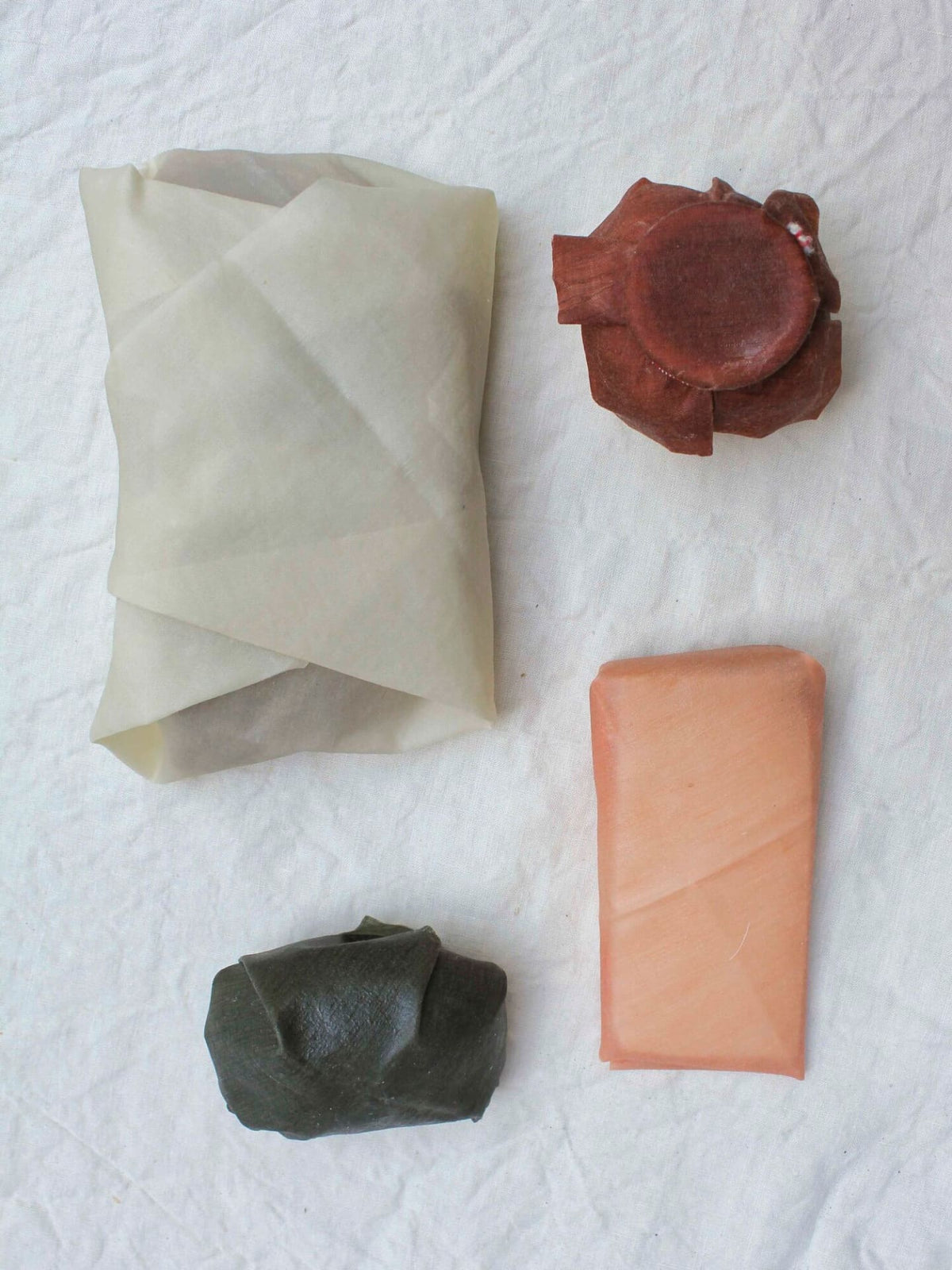 Four pieces of Ivy ⋄ Madder ⋄ Indigo Waxed Linen Food Wraps displayed on a white background as a sustainable alternative to plastic clingfilm by Wax Atelier.