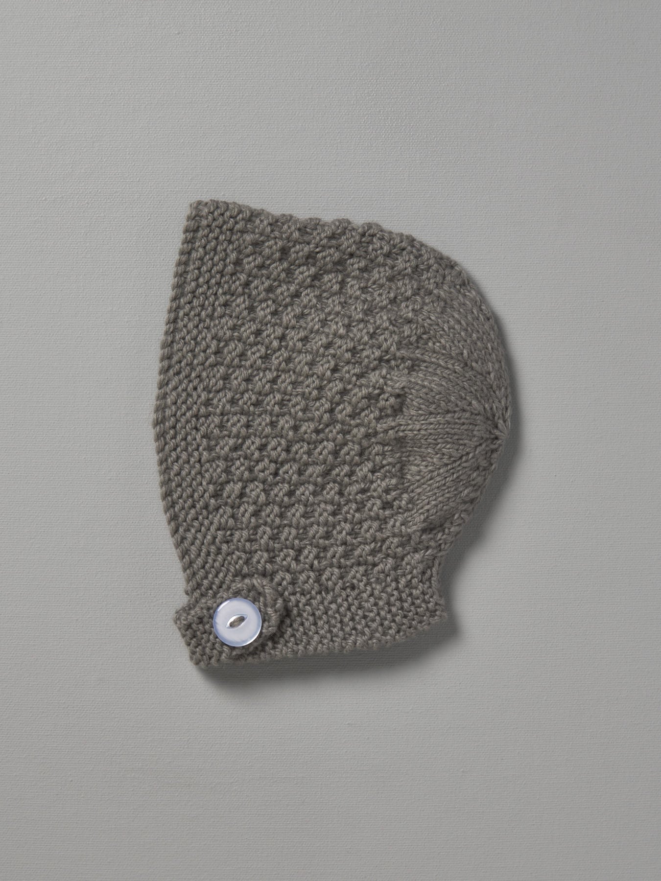 A grey hand knitted baby bonnet - Mushroom with a button on it by Weebits.