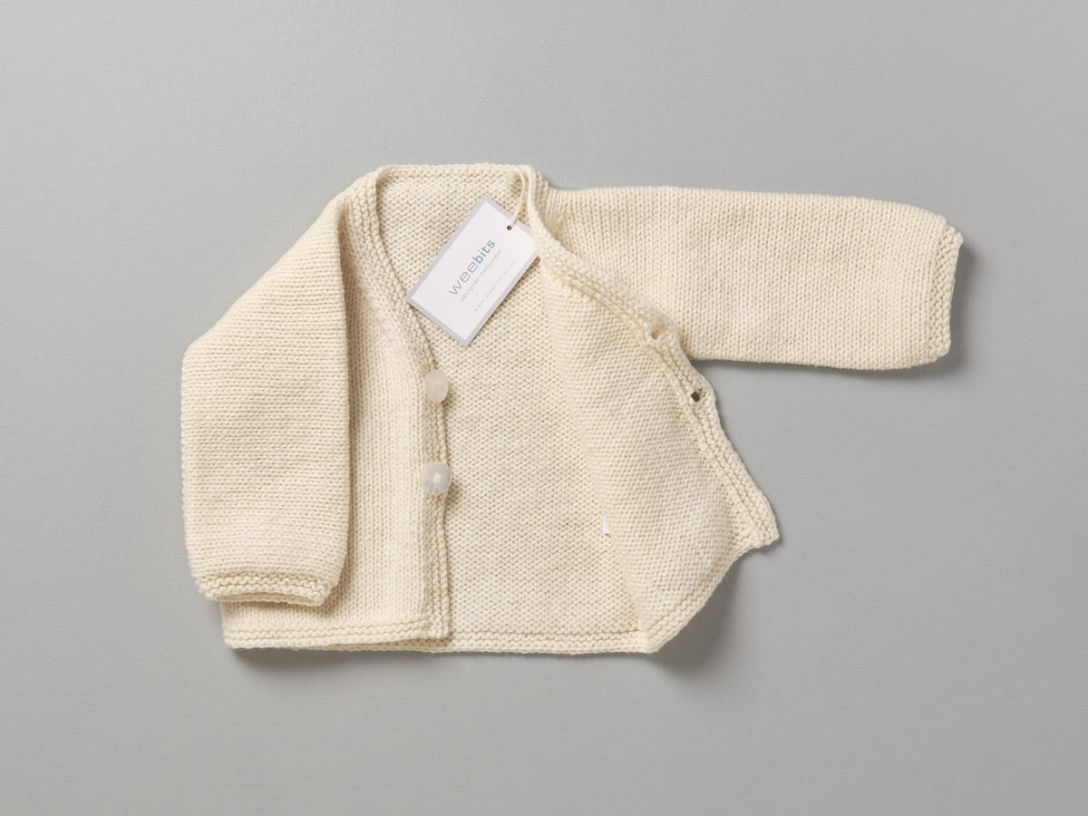 A Hand Knitted Baby Cardigan - Natural by Weebits with a tag on it.