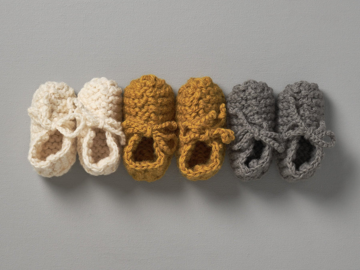A row of Weebits Hand Knitted Chunky Booties - Mushroom in different colors.