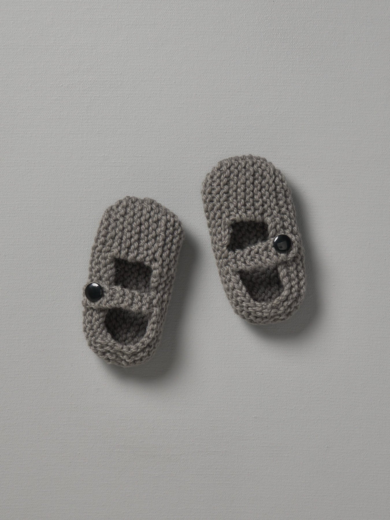 A pair of Weebits Hand Knitted Mary Jane Shoes in Mushroom color on a white surface.