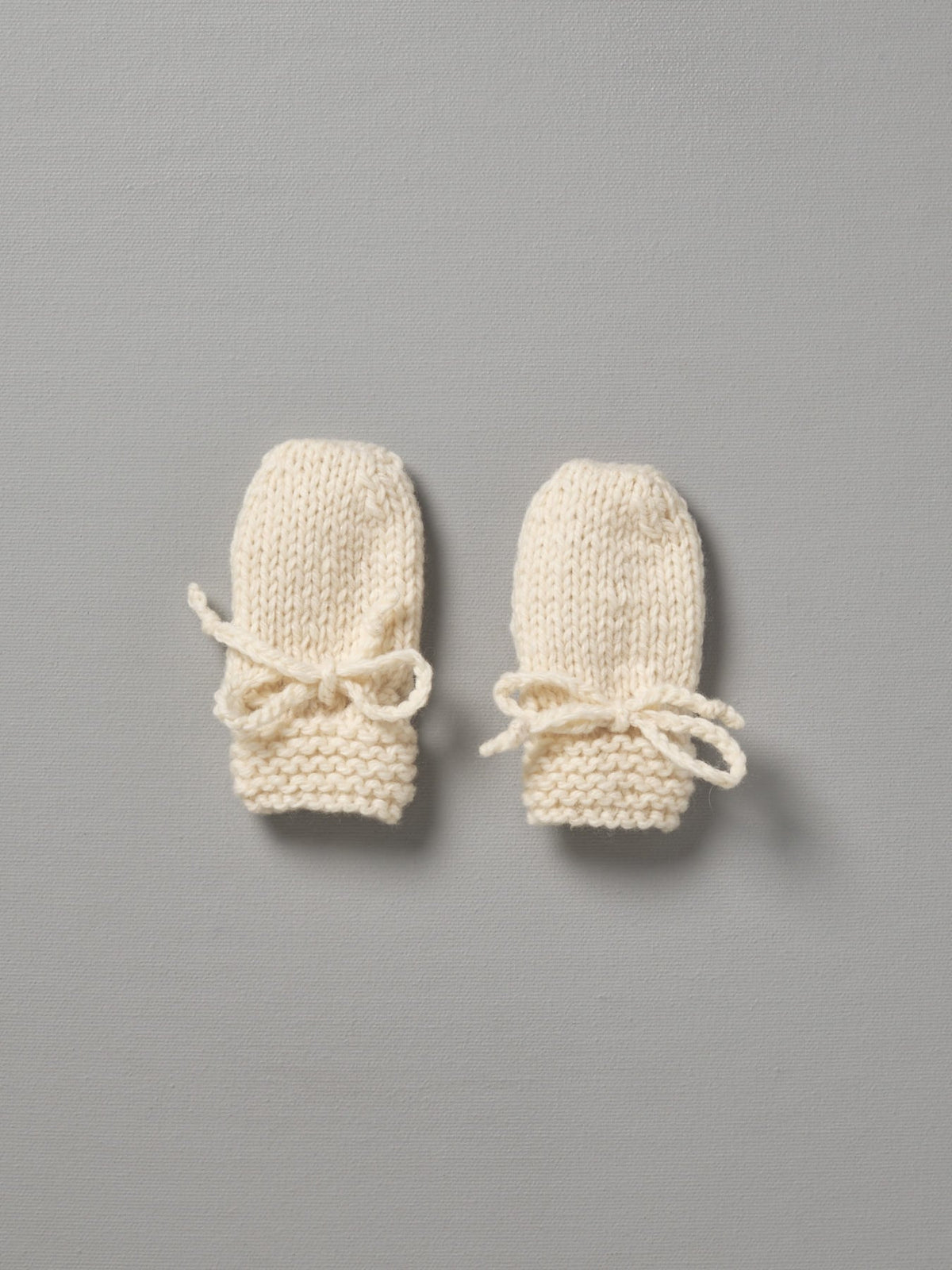 Two Weebits Hand Knitted Mittens on a grey background.