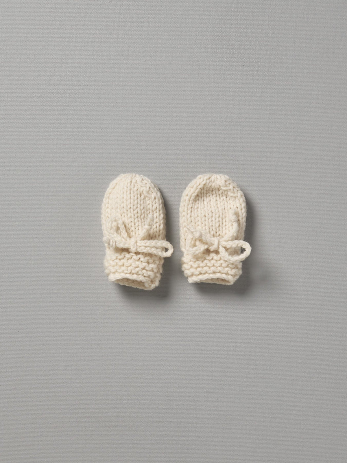 Two Weebits Hand Knitted Mittens on a grey surface.