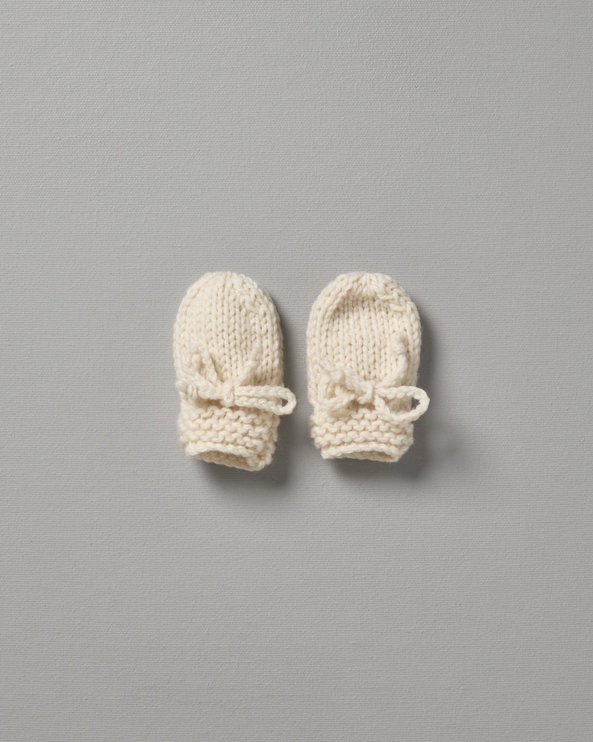 Two Weebits Hand Knitted Mittens on a grey surface.