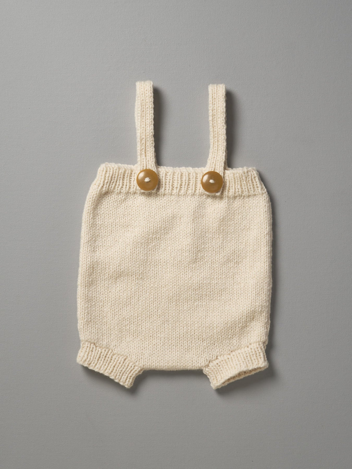 A Weebits Hand Knitted Romper - Natural with buttons on it.
