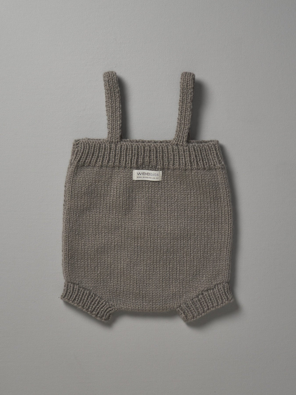 A Mushroom Weebits Hand Knitted Romper on a grey background.
