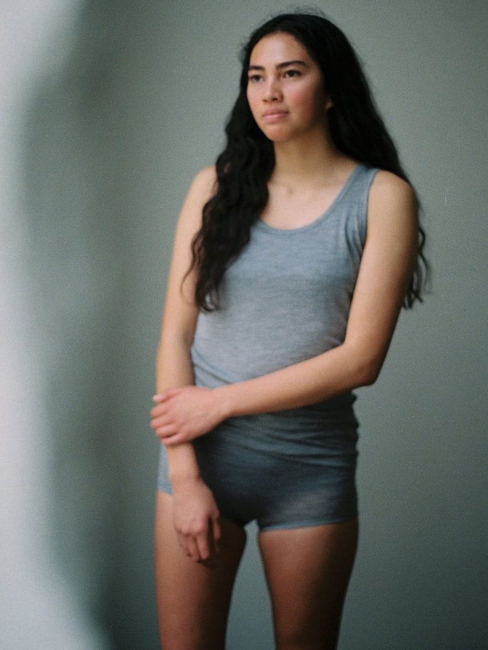 A young woman wearing a Huia Merino Tank Top - Grey by YARN nz and shorts.