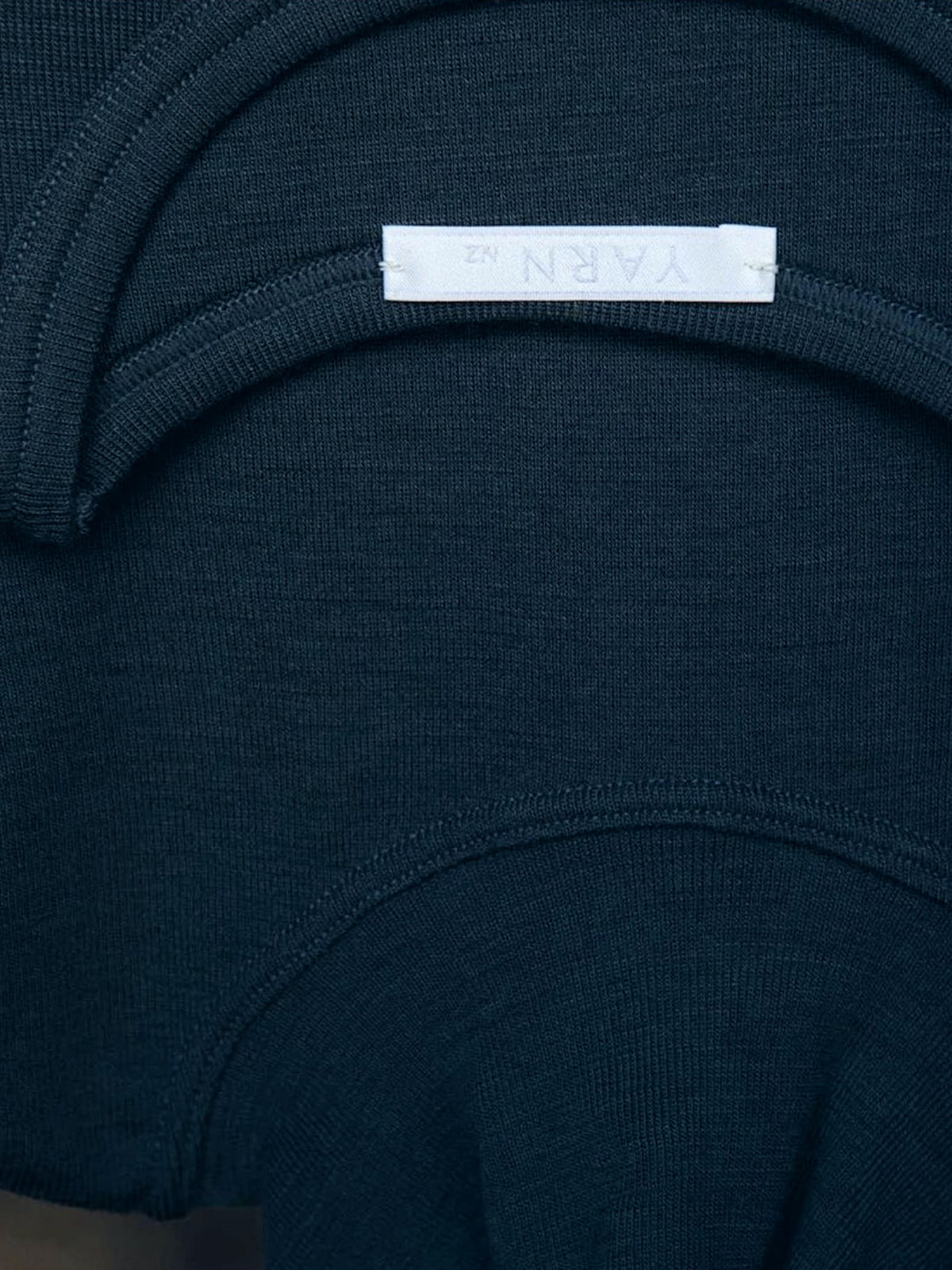 The back of a Tui Fine Merino Rib Turtle - Black sweater with a YARN nz label on it.