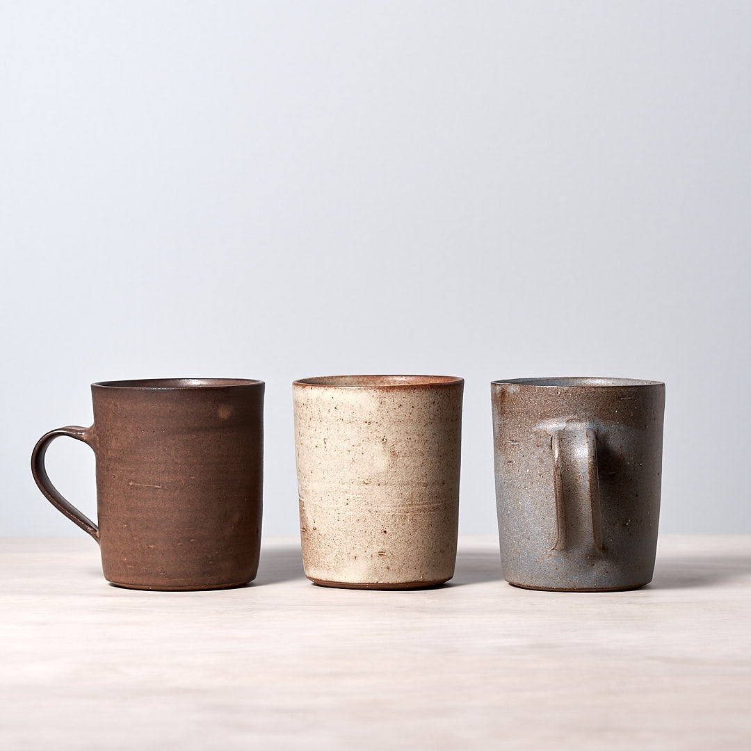 Three Grey-blue mugs sitting on a wooden table. (Brand: Zoë Isaacs)
