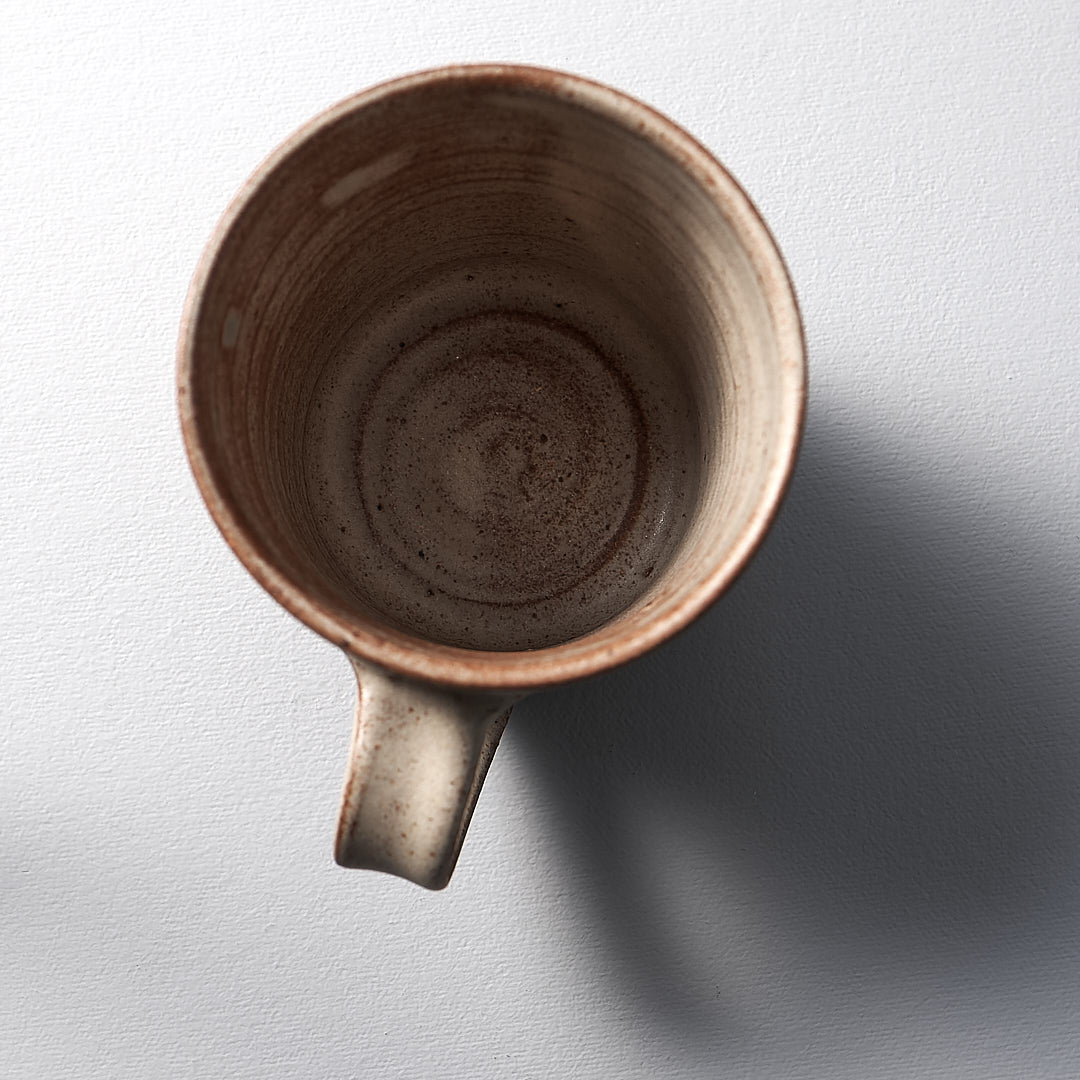 A cream Zoë Isaacs mug on a white surface.