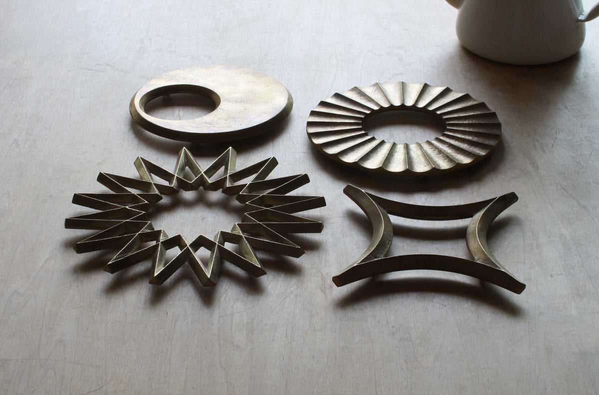 A set of Sun Trivet – Solid Brass coasters by Futagami on a table.