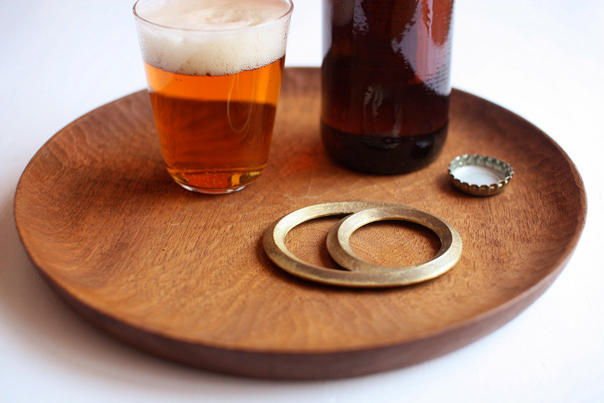 A Futagami Eclipse Bottle Opener – Solid Brass on a wooden tray.